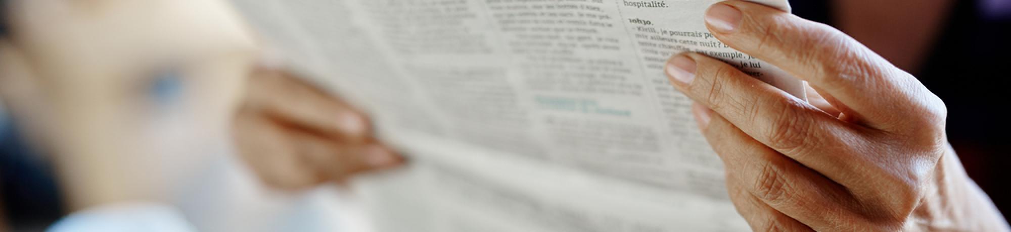 Newspaper broadsheet held and read by senior female